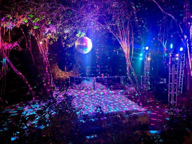 an outdoor stage set up for a party with colorful lights and disco balls on the ground