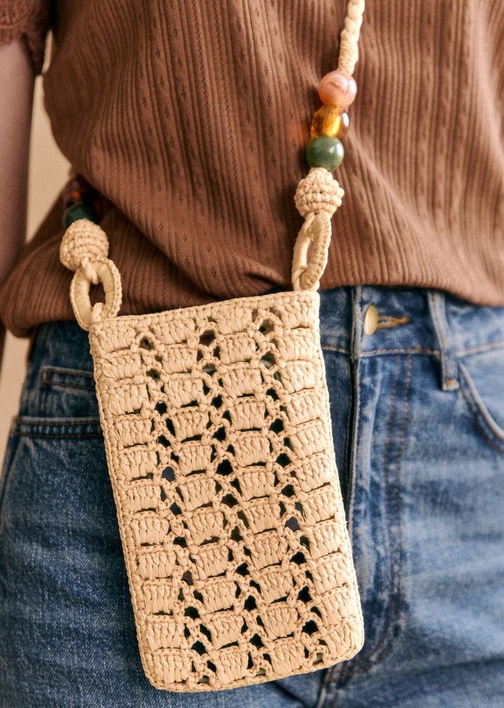 a woman is holding a crocheted bag in her hands and wearing a brown shirt