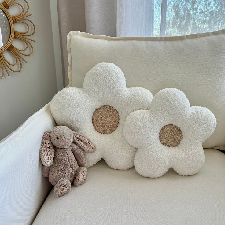 two stuffed animals sitting on top of a white couch next to pillows and a mirror