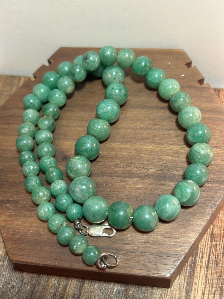 This is a beautiful, vintage, genuine, natural green jade and sterling silver necklace that is 17 1/2 inches. The necklace features natural green jade beads in different sizes that are high-quality and a gorgeous green color. The jade beads range in size from 1/2" in diameter or 17.7mm to 3/8" in diameter or 9.5mm to a little more than 1/4" in diameter or 6.5mm. The necklace weighs an impressive 50.5 grams and is stamped 925. It also has been tested and is genuine jade and sterling silver.  Jade is believed to promote feelings of love, compassion, and self-love, connecting us to our higher selves and fostering a sense of unity with the world around us. Its spiritual properties also include confidence, acceptance, health, and the ability to resolve emotional or spiritual issues. It is also Jade Emerald Necklace With Round Beads For Healing, Emerald Necklace With Round Aventurine Gemstone Beads, Emerald Necklace With Aventurine Gemstone Beads, Green Jade 8mm Beads Jewelry, Hand-strung Round Jade Bead Necklaces, Hand-strung Turquoise Jade Beaded Necklace, Bohemian Style Hand-strung Jade Necklaces, Hand-strung Green Jade Beads, Sterling Necklaces