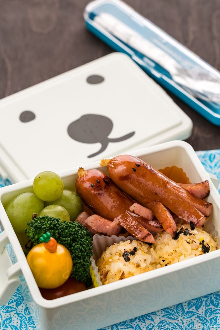 a bento box with sausages, rice and veggies next to a bear shaped container