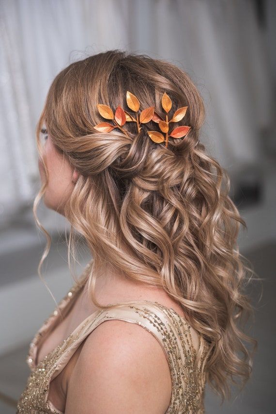 a woman with curly hair and orange flowers in her hair is wearing a gold dress