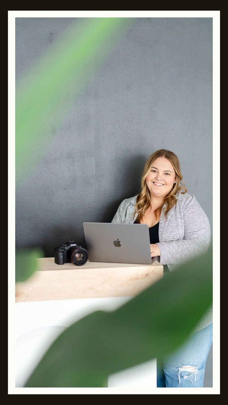 a woman sitting at a table with a laptop computer in front of her, smiling