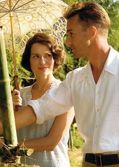 a man standing next to a woman holding an umbrella