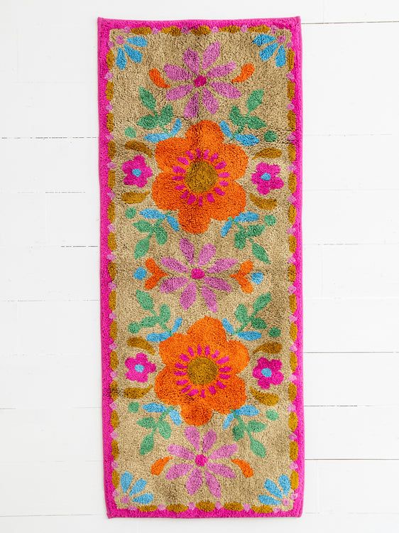 a colorful rug hanging on the wall next to a white brick wall with a pink border