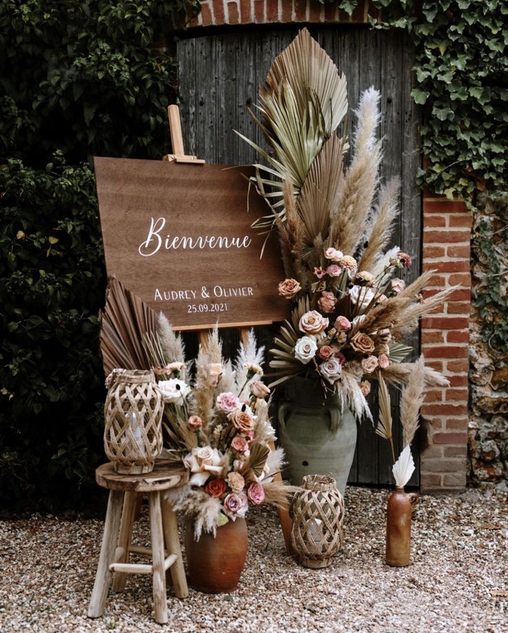 a sign that is sitting next to some flowers and plants in front of a building