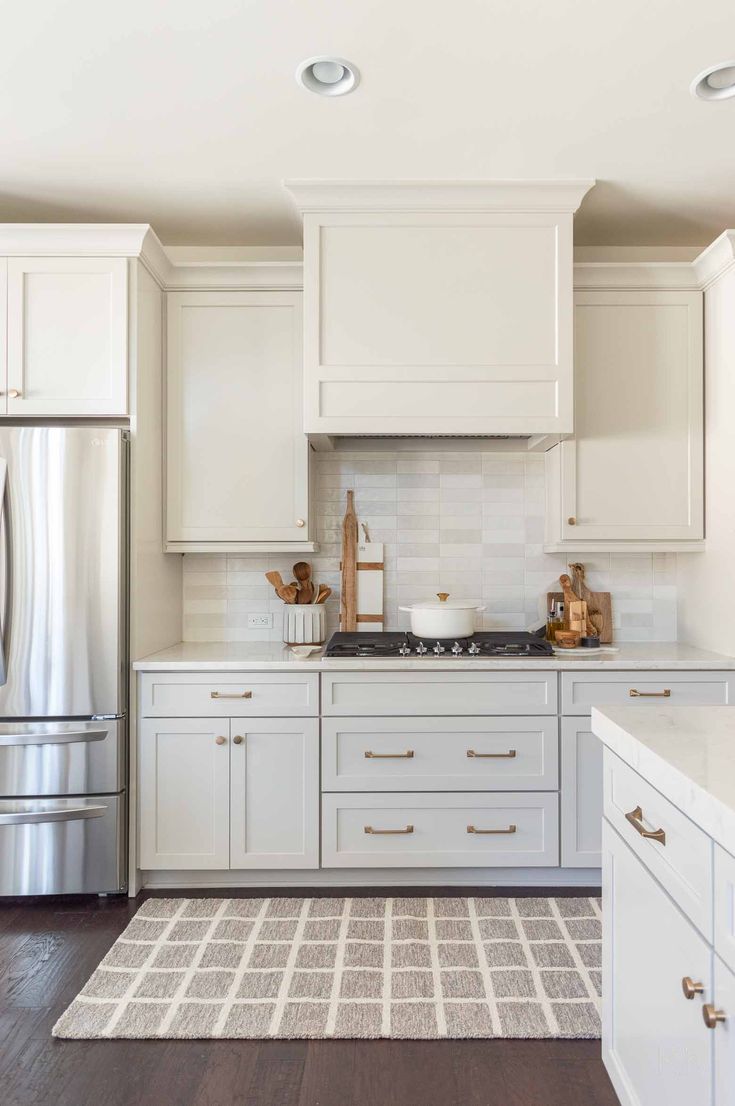 a kitchen with white cabinets and stainless steel refrigerator freezer next to an area rug