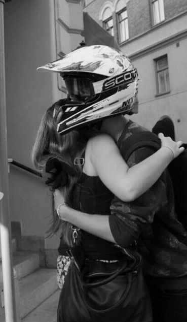 two people hugging each other with helmets on their heads and one person wearing a motorcycle helmet