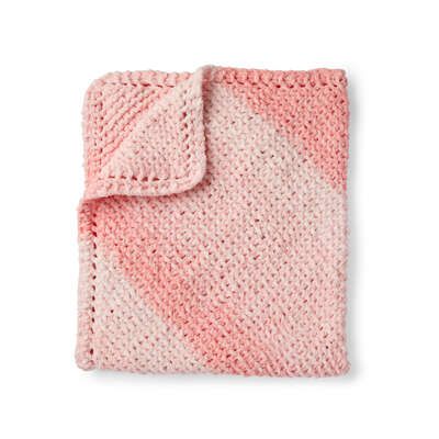 a pink and white knitted blanket on a white background with a diagonal design in the middle