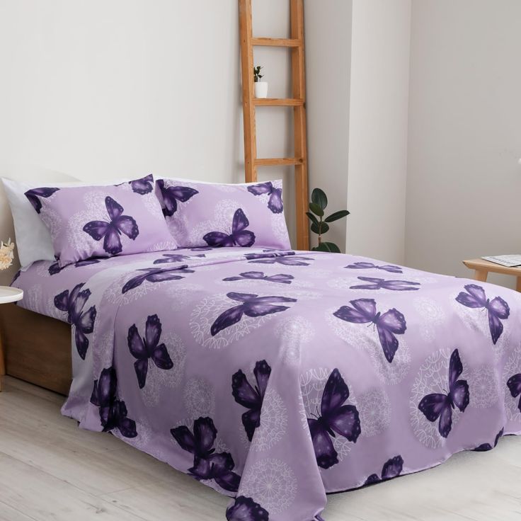 a bed with purple butterflies on it in a room next to a table and chair