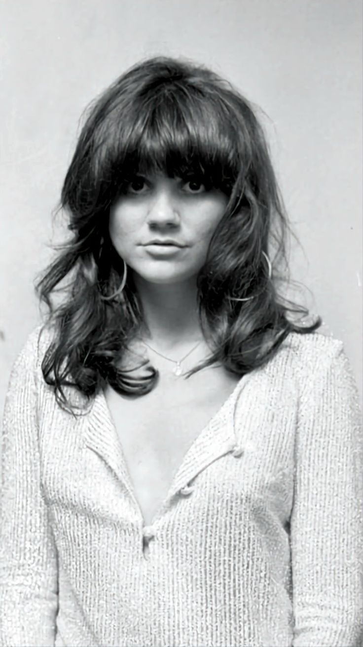 black and white photograph of a woman standing in front of a refrigerator with her hands on her hips