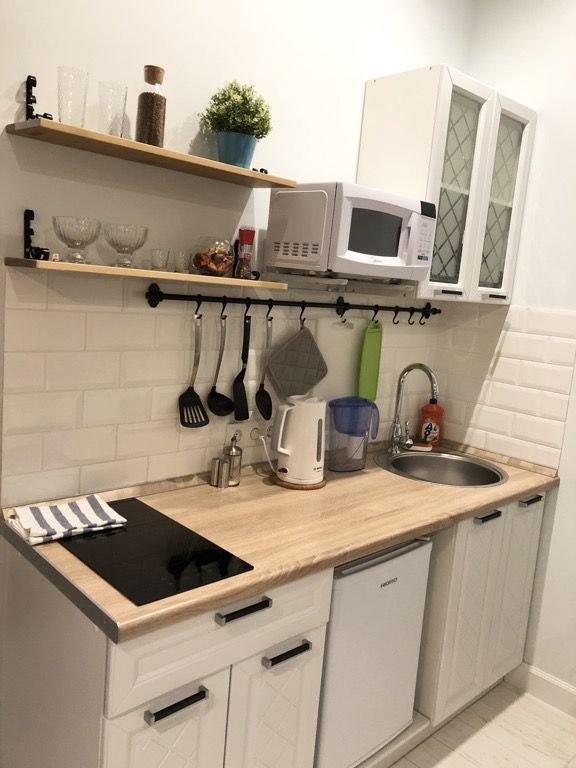 a kitchen with white cupboards and wooden counter tops, including a microwave above the sink