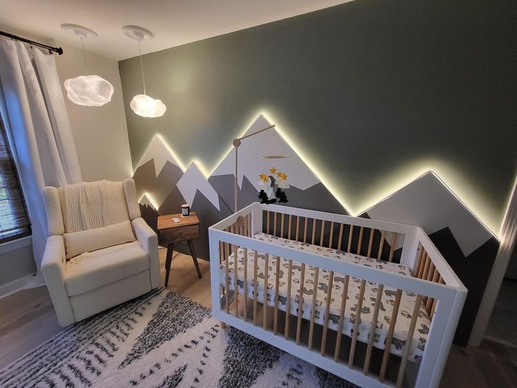 a baby's room with mountains painted on the wall and a white crib