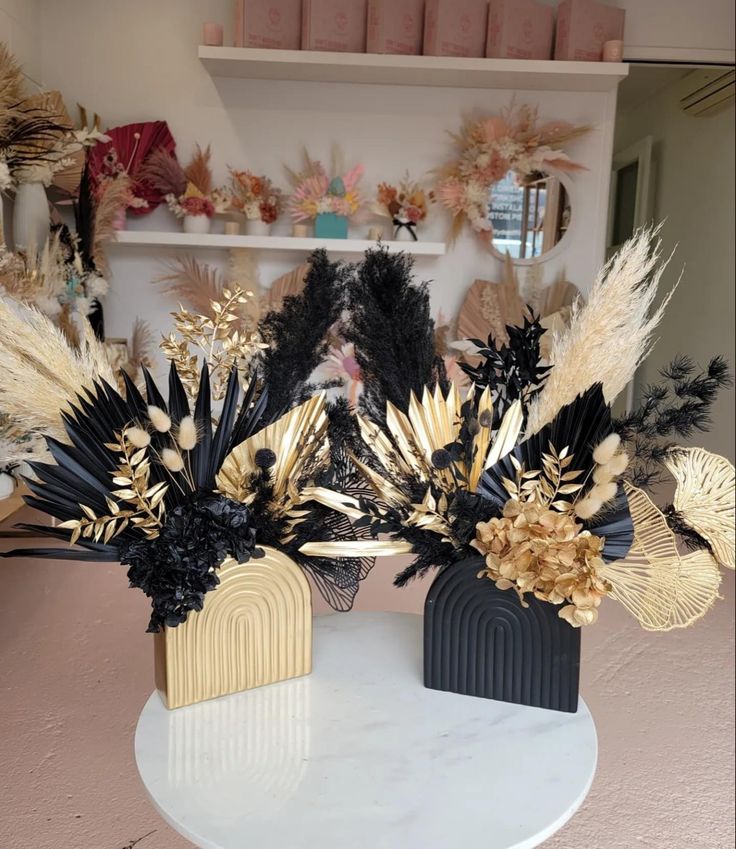 two black and gold vases sitting on top of a white table next to each other