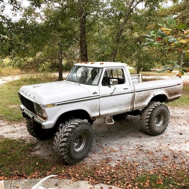 an old white pickup truck parked in the woods