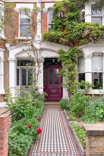 a red door is in the middle of a checkerboard floored garden path