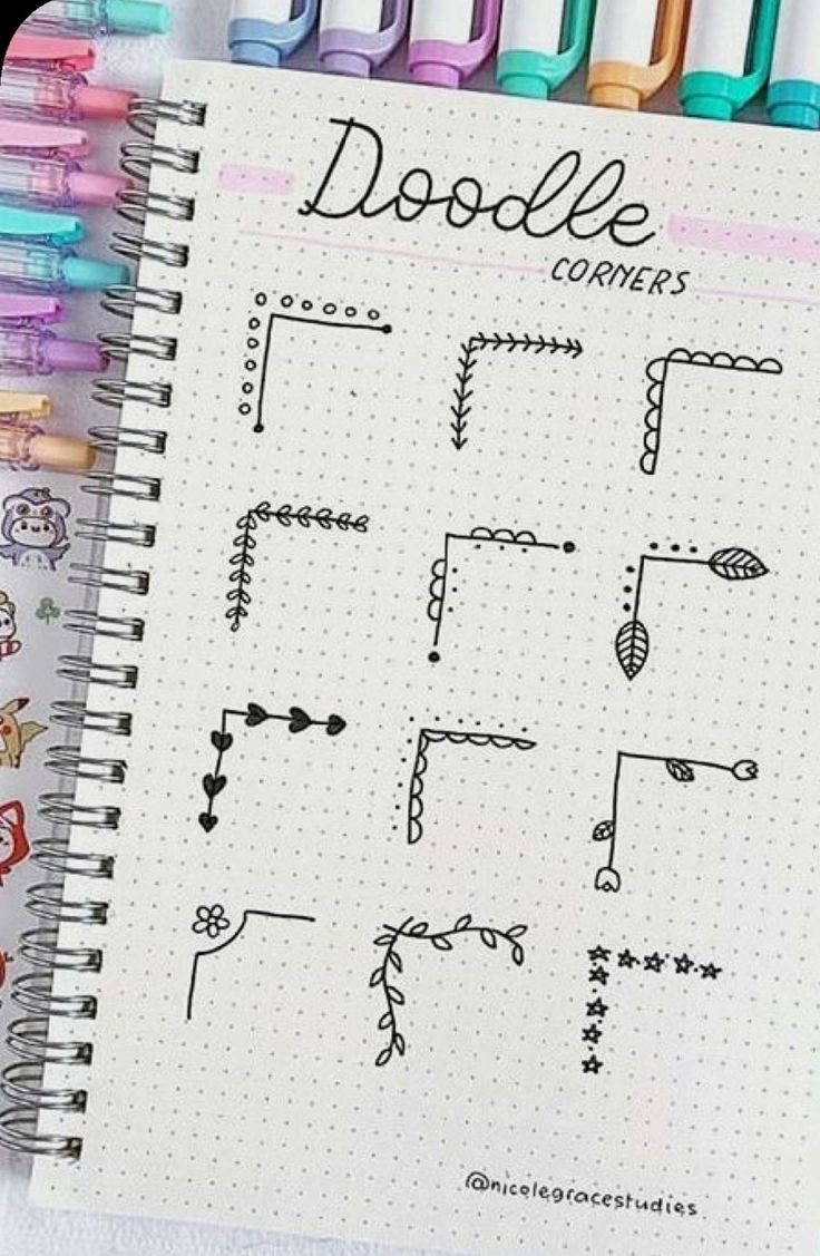 a spiral notebook with doodle corner designs on it next to markers and pencils