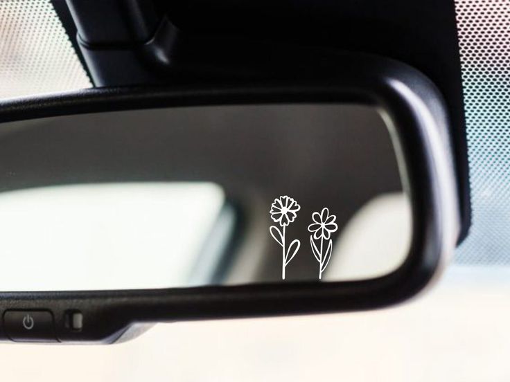 a side view mirror with some flowers on the side and one flower in the middle