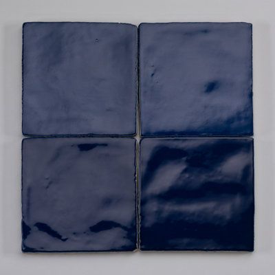 four square blue ceramic tiles on a white wall, each with different shapes and sizes