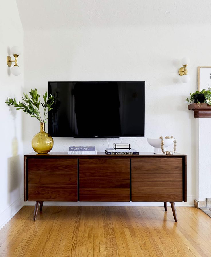 a flat screen tv sitting on top of a wooden cabinet in front of a fireplace