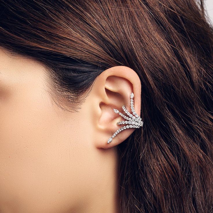 a close up of a person wearing a pair of ear cuff with diamonds on it