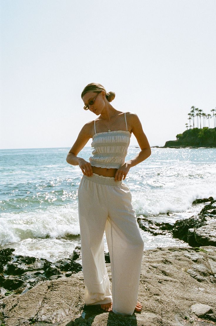 FINAL SALE. Elevate your warm weather wardrobe with the Vero Woven Smocked Tank Pants Set. This matching set features smocked detailing with contrasting stitching, adding a touch of effortless to your look. Summer Vacation Smocked Top With Gathered Waist, Chic Summer Pants With Smocked Back, Casual Bottoms With Smocked Back For Daywear, Chic Smocked Top With Cuffs For The Beach, Chic Smocked Top With Smocked Cuffs For Beach, Chic Smocked Cuffs Top For Beach, Chic Smocked Top With Elastic Waistband For Day Out, Chic Smocked Top For Day Out With Elastic Waistband, Chic Cropped Smocked Top For Beach