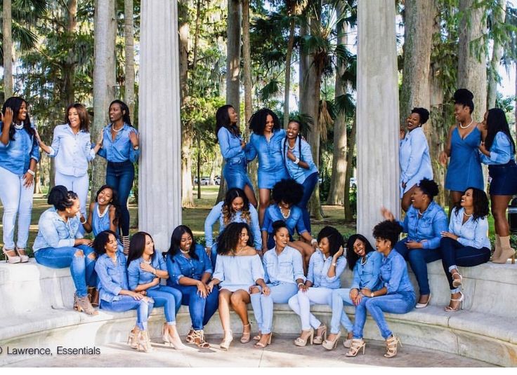 a group of women posing for a photo in front of some columns and trees with blue outfits