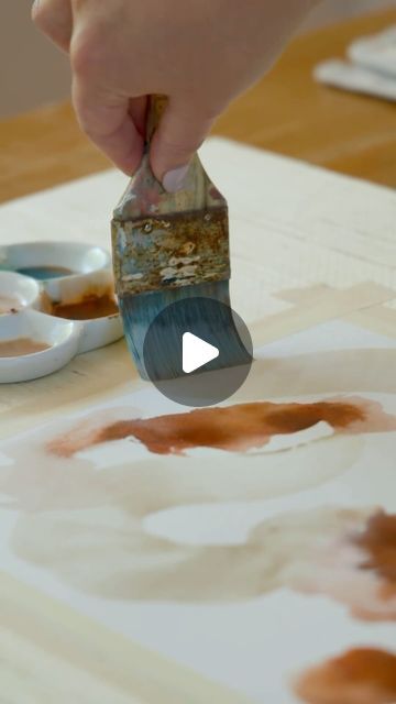 a person is painting on a table with brown paint