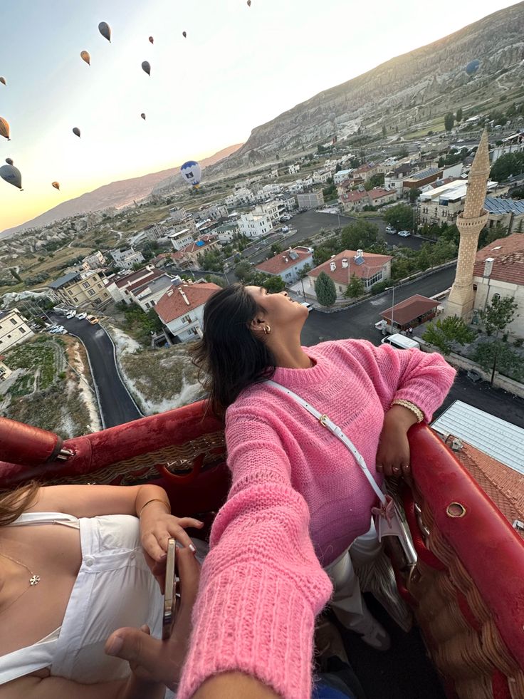 two women sitting in the back of a truck looking at hot air balloons flying above them