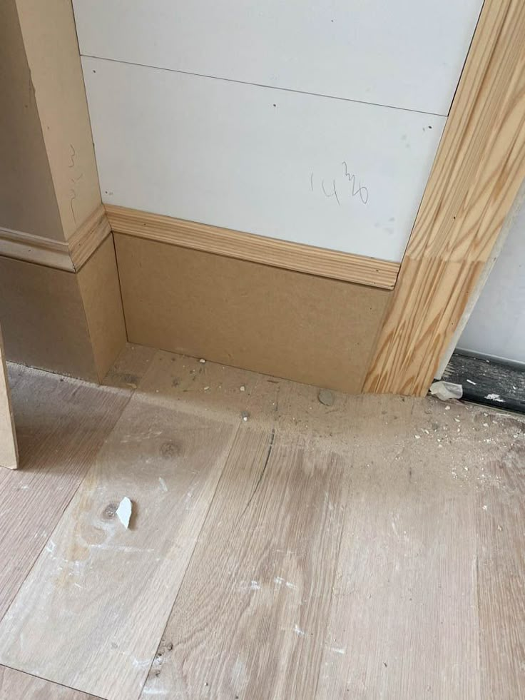 the corner of a room with wood flooring and white paint on the wall behind it