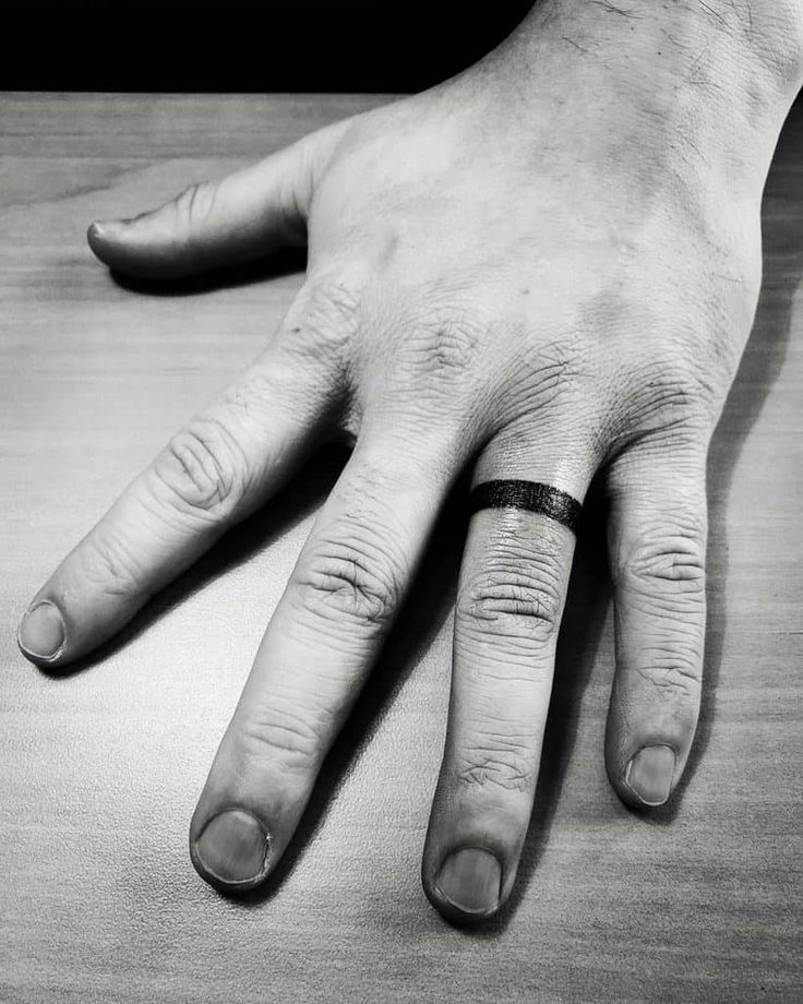 black and white photograph of a person's hand with two rings on their fingers