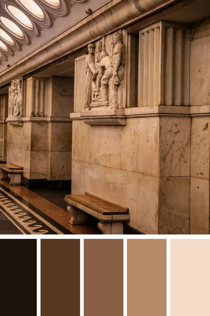 the interior of a subway station with benches and sculptures on it's walls, along with several different shades of brown