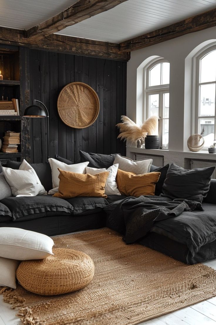 a living room filled with lots of black furniture and white pillows on top of a rug