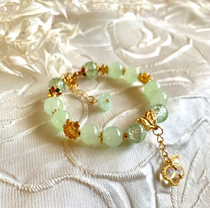 Beautiful jade and green cracked marbled beads bracelet with gold colored flowers. Rainbow butterfly charm. 100% hand made. Good gift for friends or family. Gold Jade Beaded Bracelets For Spiritual Purposes, Gold Jade Beaded Bracelets For Spiritual Wear, Spiritual Gold Jade Beaded Bracelets, Handmade Gold Aventurine Beaded Bracelets, Gold Aventurine Round Bead Bracelets, Gold Beaded Bracelets With Jade Natural Stones, Gold Jade Beaded Bracelets With Natural Stones, Gold Aventurine Bracelets As Gift, Handmade Green Aventurine Bracelets