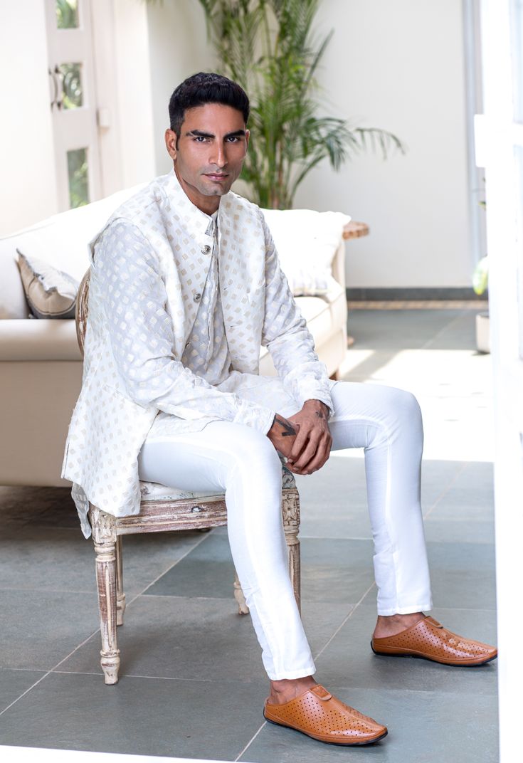 Embroidered bundi jacket in a white and gold art silk base fabric. This jacket is paired with a matching kurta and white pants.
 

Size Chart For Men





	
	
					Men's Size Chart
		

		
		
						
				Size Chart For Men
				Custom Size Measurement Guide
			
			
				
				
				Custom Size Measurement Guide
1. Take your measurements at ease…don’t hold your breath!
2. Be a little generous with the measurements. It’s always easier to take the garment in than to take it out.
3. We do rely on our clie Designer Wear Fitted White Nehru Jacket, Designer White Fitted Nehru Jacket, Designer Fitted White Nehru Jacket, White Fitted Nehru Jacket For Designer Wear, White Bandhgala With Gota Work For Festive Occasions, Elegant White Nehru Jacket Straight Kurta, Designer White Bandhgala With Naqshi, Festive White Bandhgala With Gota Work, White Fitted Nehru Jacket For Transitional Season