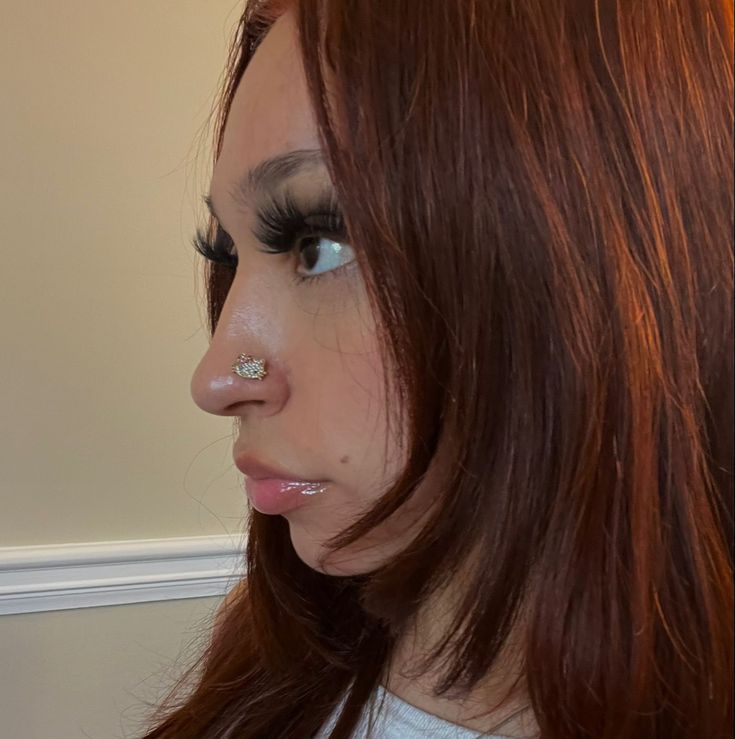 a woman with red hair and piercings on her nose