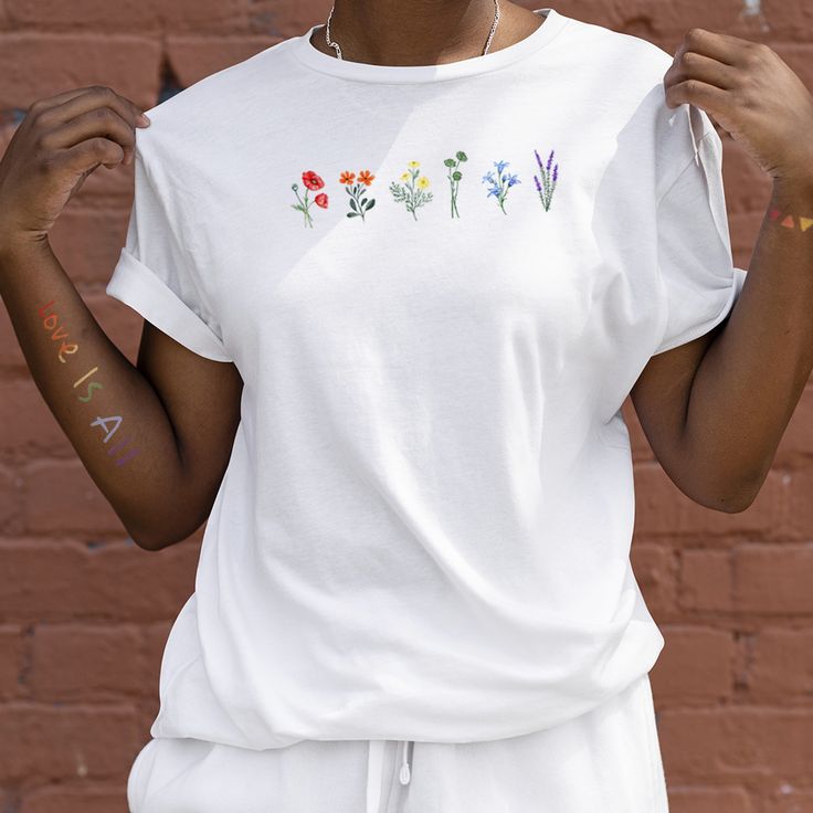 a woman wearing a white t - shirt with flowers painted on the front and side