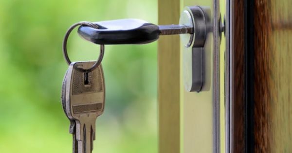 an open door with a key hanging from it's side and a window in the background