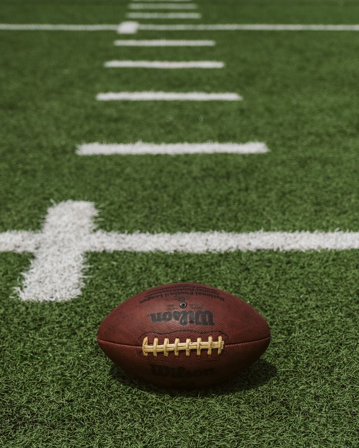 a football sitting on top of a green field next to a line of white lines