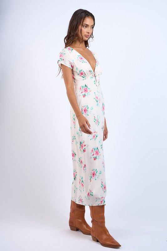 Discover effortless charm with our Floral V-Neck Front Tie SS Midi Dress. Featuring a delicate floral print and a modern v-neck with tie detail, this dress is both stylish and comfortable. With its short sleeves and back zipper, it's easy to slip on and off. Perfect for any occasion, the straight long midi dress is a must-have addition to your wardrobe. Material: 100% Rayon / Lining: 100% Polyester Ditsy Floral Print V-neck Dress For Garden Party, V-neck Printed Floral Dress For Garden Party, Elegant V-neck Midi Dress With Ditsy Floral Print, Feminine Fitted Floral Print V-neck Dress, Chic Floral Print V-neck Dress For Brunch, V-neck Midi Dress With Ditsy Floral Print For Summer, Chic Floral Printed V-neck Dress, Spring Floral Print Maxi V-neck Dress, Chic Flowy V-neck Dress With Floral Print