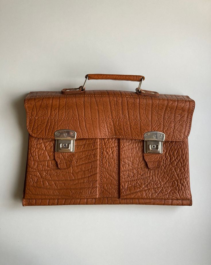 "♥ Vintage top handle unisex office briefcase/messenger bag in light brown with a gorgeous embossed texture. ♥ Can be used as a fancy laptop bag. ♥ 1 main compartment, 2 side pockets. ♥ 2 metal side closures in silver-shaded metal (there are 3 closing levels, depending how full the bag is). ♥ Looks like it is made partly of genuine leather, because after a \"water drop\" test, certain portions of the bag absorbed the water (leather is porous and therefore absorbs water, otherwise water will simp Brown Rectangular Shoulder Bag With Top Carry Handle, Everyday Textured Leather Satchel Briefcase, Brown Rectangular Briefcase, Light Brown Shoulder Bag For Business, Brown School Satchel With Luggage Sleeve, School Brown Satchel With Luggage Sleeve, Rectangular Textured Leather Satchel For Office, Brown Briefcase With Top Handle And Luggage Sleeve, Brown Briefcase With Luggage Sleeve