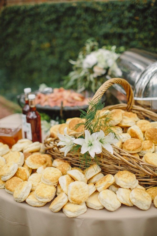 a table topped with lots of food next to a basket filled with bread and flowers