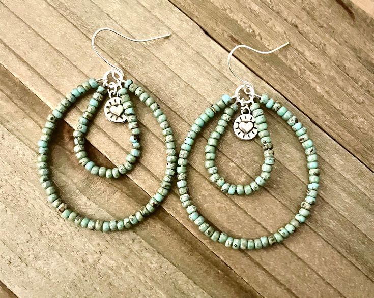 These double teardrop beaded hoop earrings are so pretty!  They are nearly 2 inches long and 1 1/2 inches wide.  The turquoise colored seed bead teardrop hoops have a small heart dangling in the middle.  I have a vast collection of seed beads.  Please message me if you would like a different color.  I probably have it, and will make a custom order for you.  We also have these hoops in different colors in the shop.  ~I use high quality hypoallergenic materials along with many different colors and Handmade Turquoise Hoop Earrings, Western Diy, Seed Bead Hoop Earrings, Earrings Handmade Beaded, Wood Hoop Earrings, Bead Hoop Earrings, Wire Wrap Jewelry Designs, Boho Hoop Earrings, Handmade Hoop Earrings