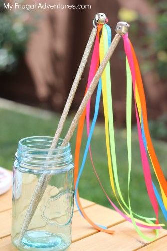 a mason jar filled with rainbow colored streamers and straws sitting on top of a wooden table