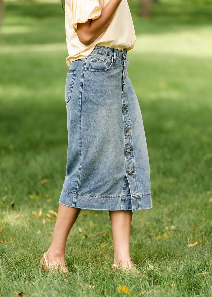 A straight button-front midi denim skirt is a classic staple for every woman’s wardrobe. The pewter buttons are functioning for the first 3 buttons and the rest are sewn in place - no need to worry about gaps between the buttons! Wear her with a classic button-up, a blouse or a tee - she will make anything look elevated! Style | Midi Color | Medium Wash SIZING TIPS Fit | Semi-Fitted Stretch | Mid-Stretch Model | True to Size Buttoned Medium Wash Denim Skirt For Fall, Fall Medium Wash Buttoned Denim Skirt, Fall Medium Wash Denim Skirt With Buttons, Spring Denim Skirt With Button Closure Medium Wash, Spring Medium Wash Button-up Denim Skirt, Spring Medium Wash Denim Skirt With Button Closure, Spring Button-up Bottoms With Snap Buttons, Spring Denim Blue Skirt With Snap Buttons, Denim Blue Skirt With Snap Buttons For Spring