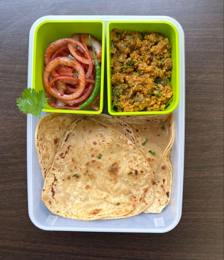 two plastic containers filled with food sitting on top of a wooden table next to a tortilla