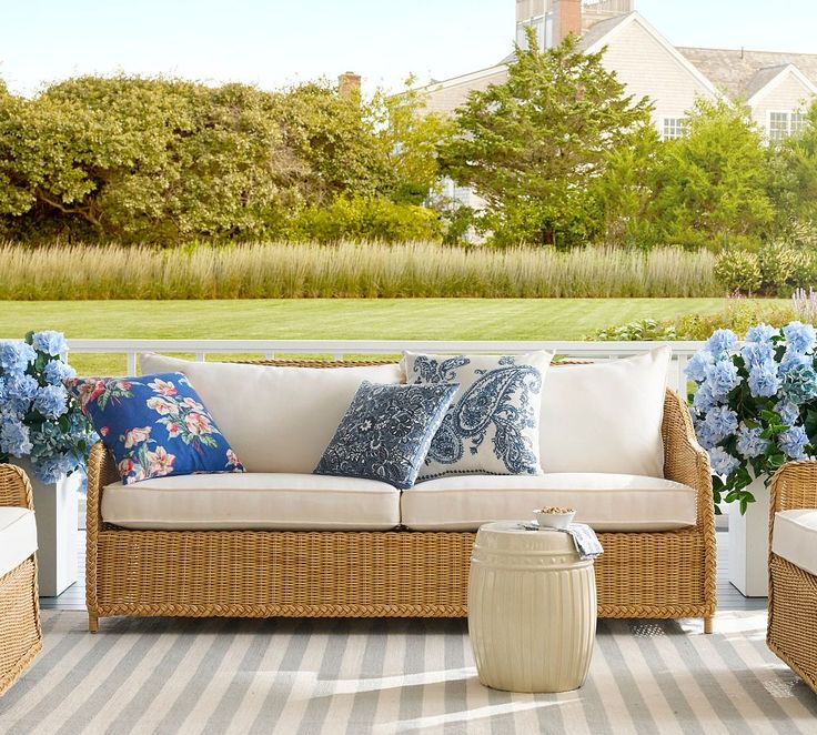 an outdoor patio with wicker furniture and blue flowers