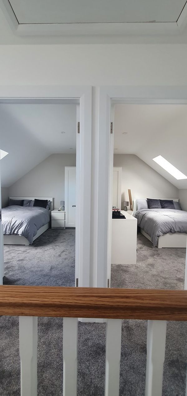 an attic bedroom with two beds in it and carpeted flooring on the other side