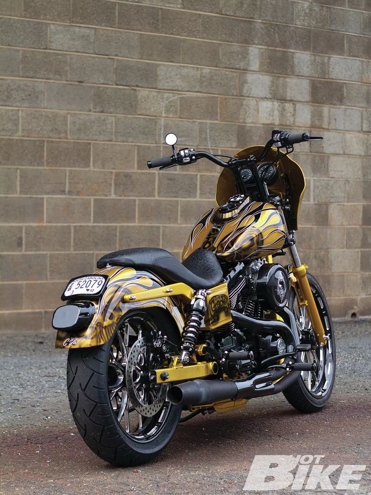 a yellow and black motorcycle parked in front of a brick wall