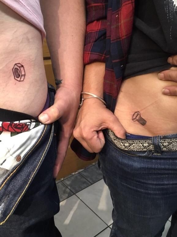 two people standing next to each other with tattoos on their stomachs and one holding the other's hand